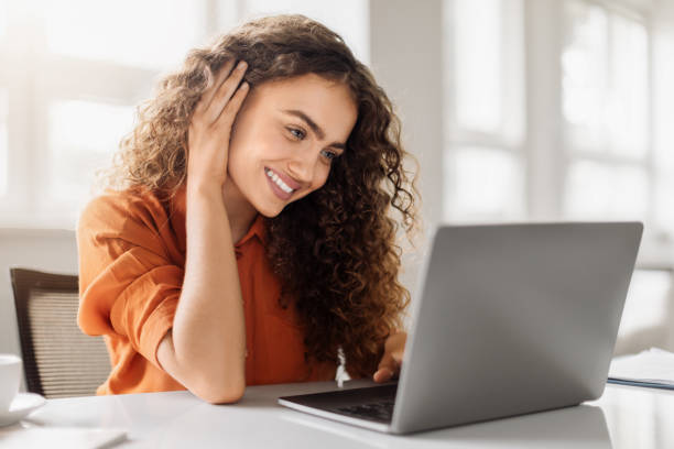 istock Smiling curly woman with laptop in office 1995838411