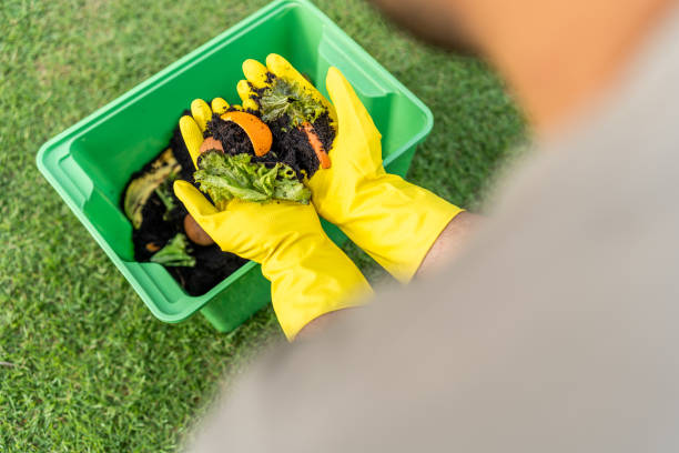 istock Ecology compost supply Kitchen waste recycling composter environmentally friendly. The young man throws leftover fruit peel egg shell and vegetables reduce waste 1995849634