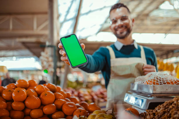 istock Stall Holder Holding Smartphone With Green Blank Screen 1995854977
