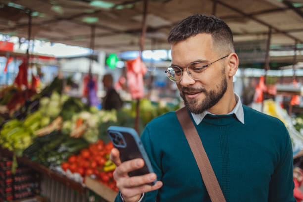 Smiling Young Man Texting at Farmer's Market