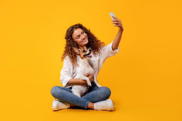 istock Woman and dog take selfie on yellow background 1995860821