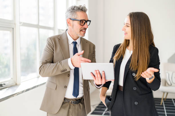 istock Grey-haired businessman engages with younger colleague, sharing a tablet 1995862907