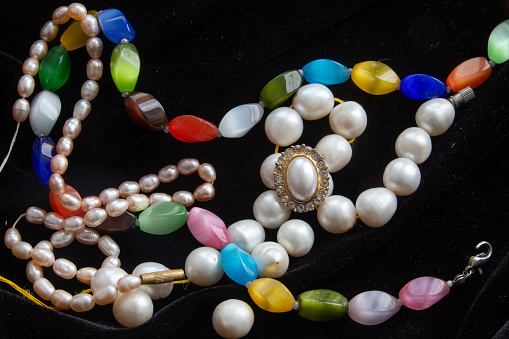 Chains of colors stones and pearls on black background  and ring with part of pearl awe memories from India