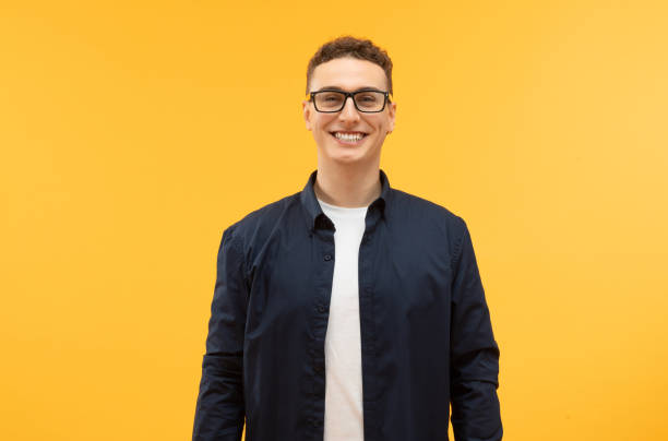 istock Stylish young guy wearing eyeglasses posing isolated on yellow background 1995890103