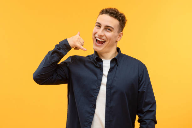 istock Handsome guy showing call me gesture, isolated on yellow 1995890619