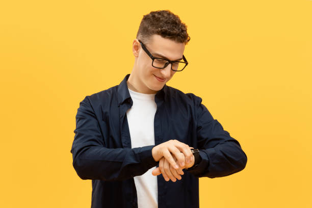 Positive young guy in eyeglasses checking time