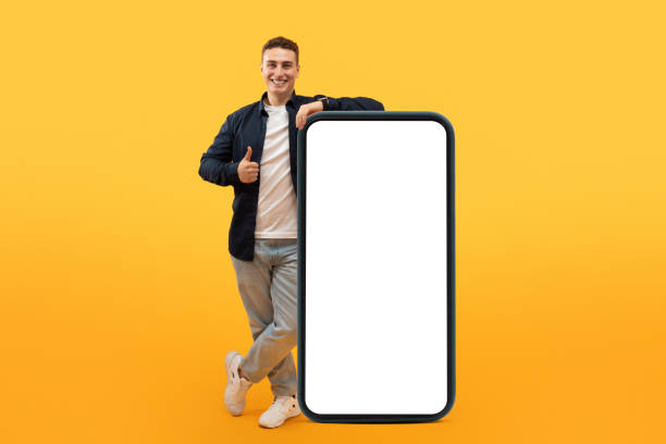 istock Excited guy stand by big smartphone with white blank screen 1995891701