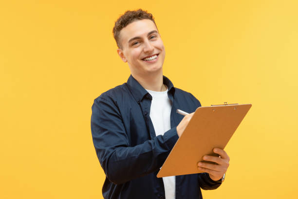 istock Positive young guy taking notes in clipboard and smiling 1995891736
