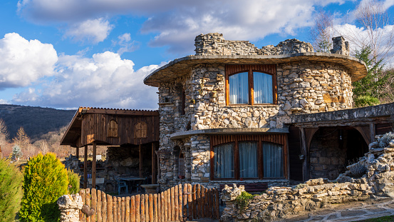 Karlukovo, Bulgaria – February 03, 2024: Stone cottage in Croatia with mountain view, fenced yard, and lush foliage