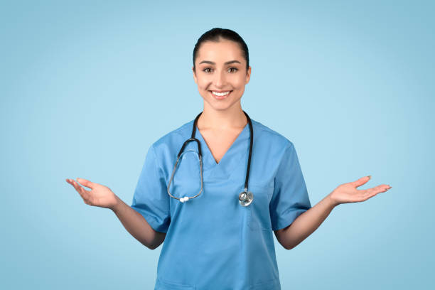 istock Smiling female nurse with open palms in blue uniform 1995923727