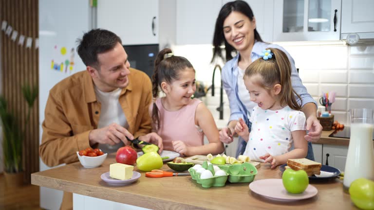 Parents with daughters making healthy breakfast and having fun  in the modern kitchen