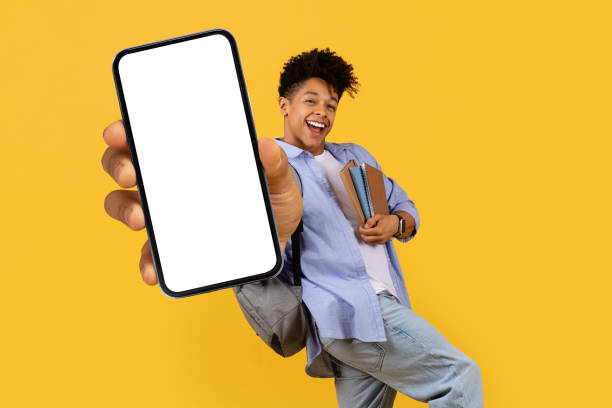 istock Happy black guy student showing smartphone screen on yellow backdrop 1995947894