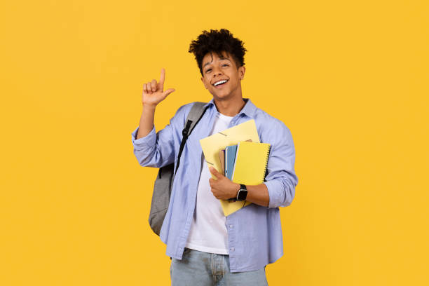 istock Cheerful student gesturing size with hand on yellow background 1995947905