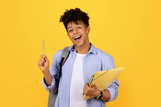 istock Cheerful black male student with pen and folders 1995948448
