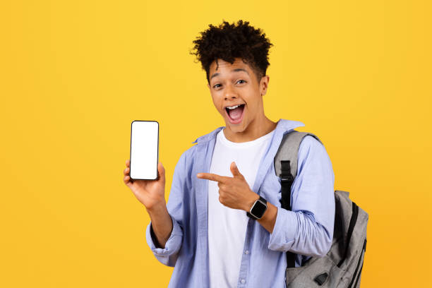 istock Excited black man student showing and pointing at phone with blank screen 1995948478