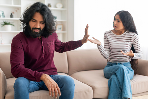 Relationship Problems. Millennial Indian Couple Arguing In Living Room, Careless Husband Ignoring Shouting Wife, Young Eastern Spouses Having Domestic Conflicts Or Suffering Marriage Crisis