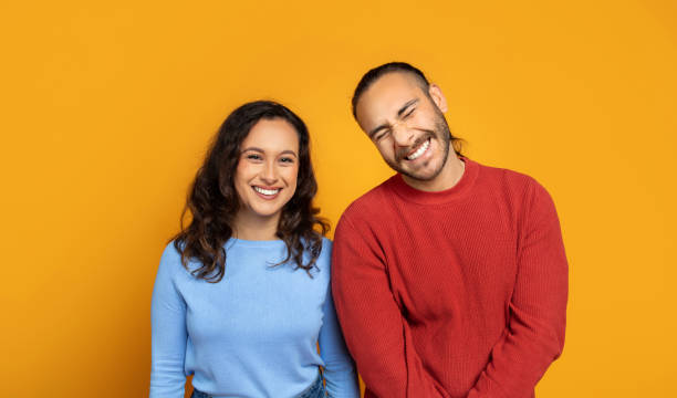 istock Cute millennial couple posing together on orange background 1995980289