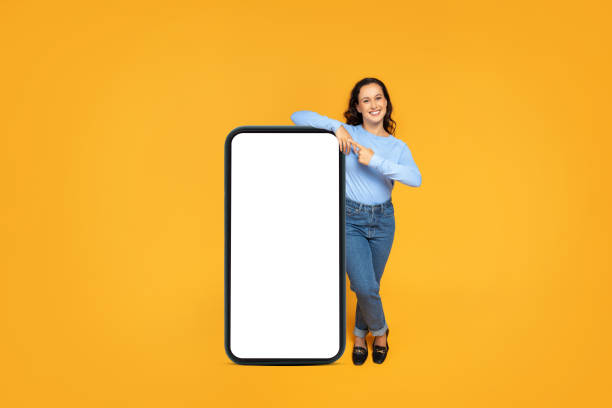 istock Positive attractive lady posing with big smartphone with empty screen 1995980315