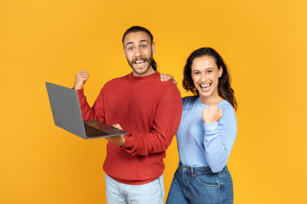 istock Excited young couple holding and using laptop 1995980855