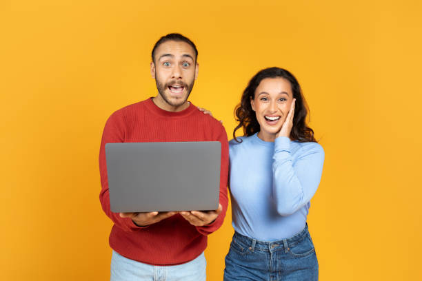istock Surprised millennial husband and wife holding laptop 1995980857