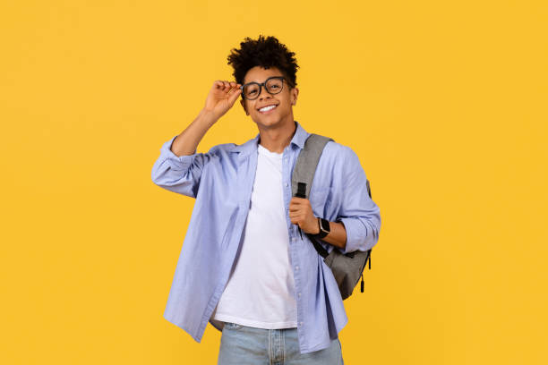 istock Confident black student adjusting glasses on a yellow background 1995982417