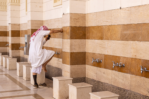 Middle East, Saudi Arabia, Madinah Province, Medina. November 20, 2023. Washing feet before entering Fash Mosque below Mount Uhud.