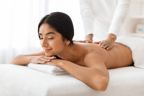 istock Attractive Indian lady experiences a soothing back rub in spa 1996005307