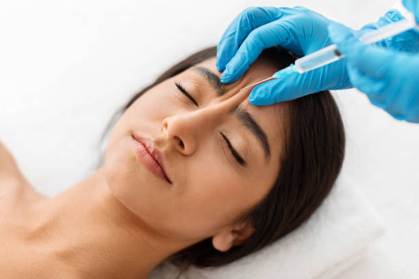 Indian woman getting cosmetic injection between eyebrows at beauty center Beautician hands making hyaluronic acid injection for glabella facial rejuvenation procedure, young indian woman getting cosmetic injection between eyebrows at beauty center, top view asian eyebrows stock pictures, royalty-free photos & images