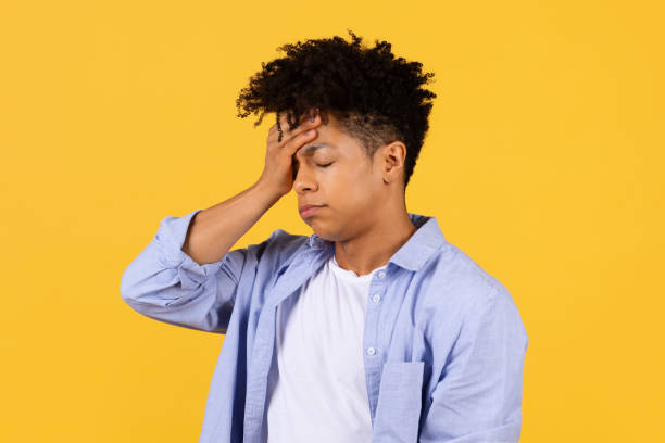 istock Stressed young black man with headache on yellow background 1996028885