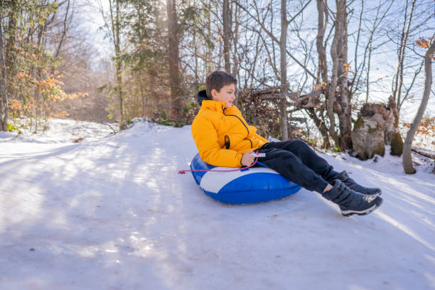 istock Boy sliding down hill on a snow tube 1996034269