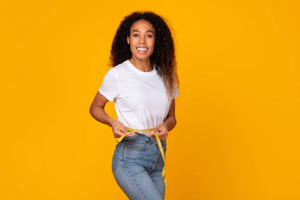 istock Black lady holds measuring tape around her slim waist, studio 1996049978
