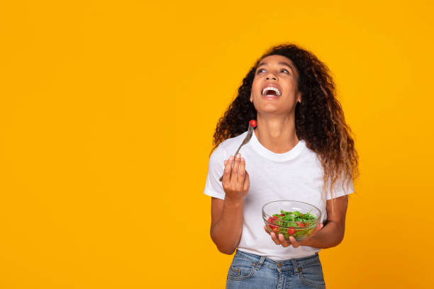 istock Black lady poses with a healthy green salad meal, studio 1996050516