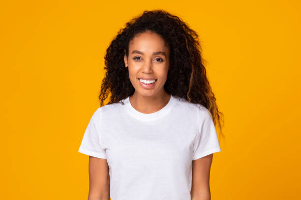 istock Black young lady with curly hair expressing positivity, yellow background 1996050523