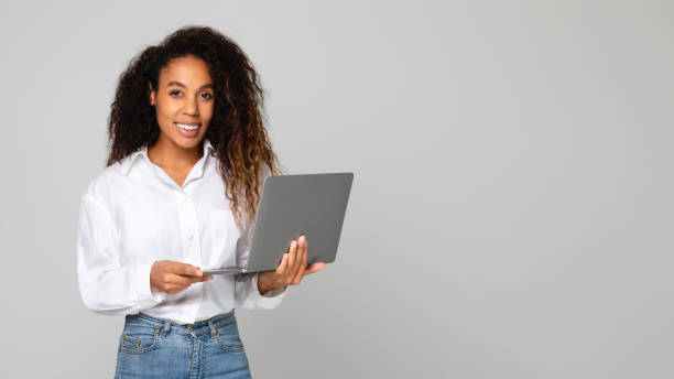 istock Black millennial lady posing with laptop pc over gray background 1996051086
