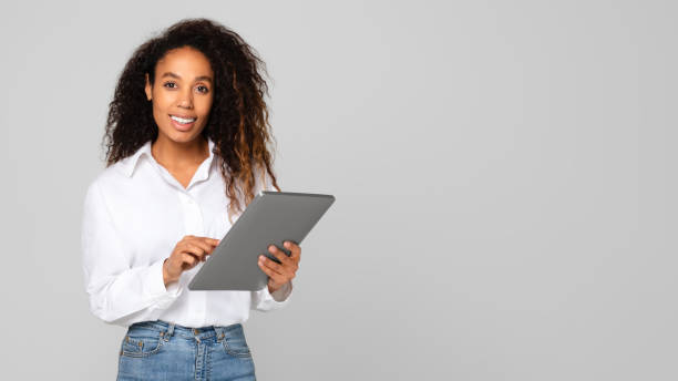 istock Black millennial lady using her digital tablet gadget, gray background 1996051090