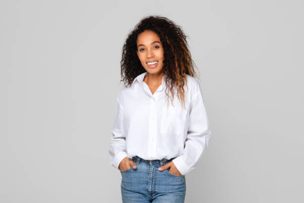 African American lady confidently smiling holding hands in pockets, studio