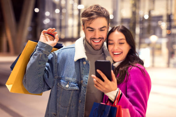 istock Spouses in winter attire using cellphone application for shopping outdoor 1996073431