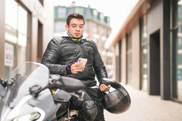 istock Young man sitting on racing motorcycle and looking at his mobile phone 1996086868