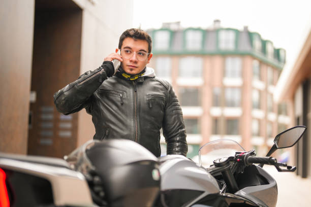 istock Young man sitting on a racing motorcycle and using his mobile phone 1996090978