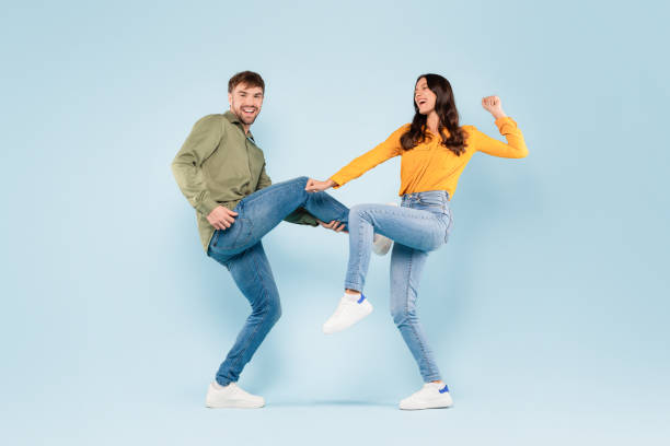 istock Playful couple dancing and laughing on blue background 1996094567