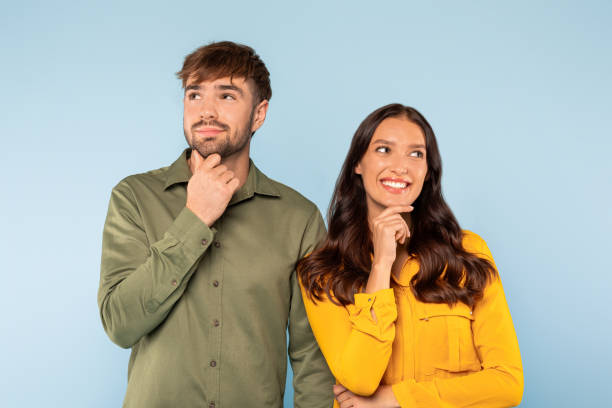 istock Thoughtful couple with curious expressions, hand on chin, looking up 1996094591