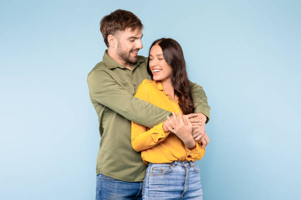 istock Loving couple embracing warmly, smiling on blue background 1996095143
