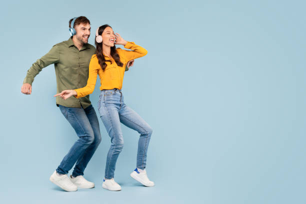 istock Happy couple dancing with headphones on blue background 1996095672