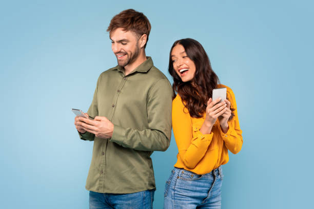 istock Woman peeks at spouse's phone, blue backdrop 1996095674