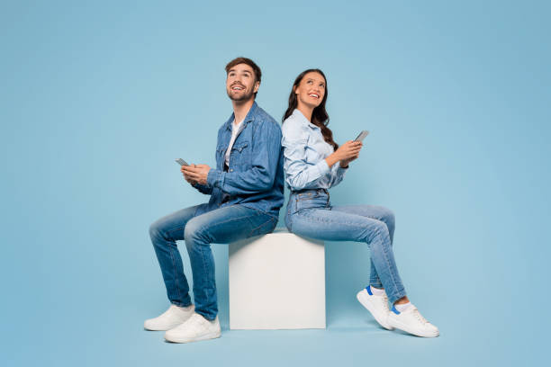 istock Spouses with mobiles gaze up, blue background 1996095683