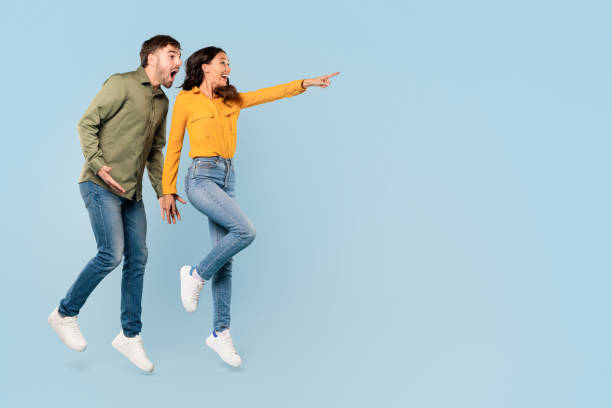istock Excited couple pointing and looking away, blue background 1996095691