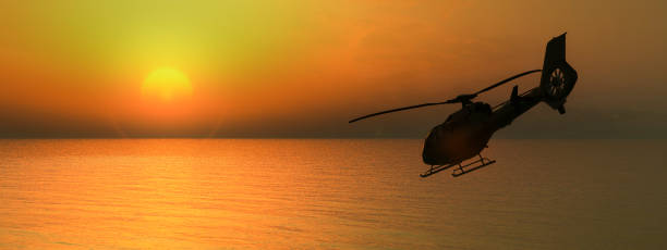 istock Twilight Flight: A Silhouetted Helicopter Soars over Calm Seas as the Sun Sets 1996105540