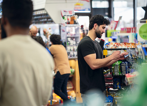 A young man selecting products to buy in a convenience store.