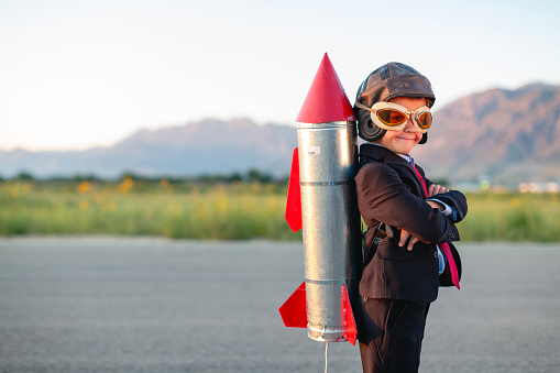 A young boy and businessman is dressed in a business suit with a homemade rocket strapped to his back. He is ready to use his smarts to launch his business to the next level. Taken in Utah, USA.