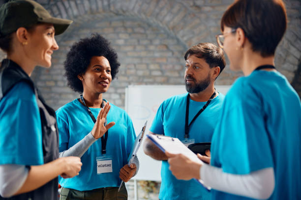 grupo multirracial de voluntários conversando enquanto trabalha no centro comunitário. - volunteer charity and relief work meeting talking - fotografias e filmes do acervo